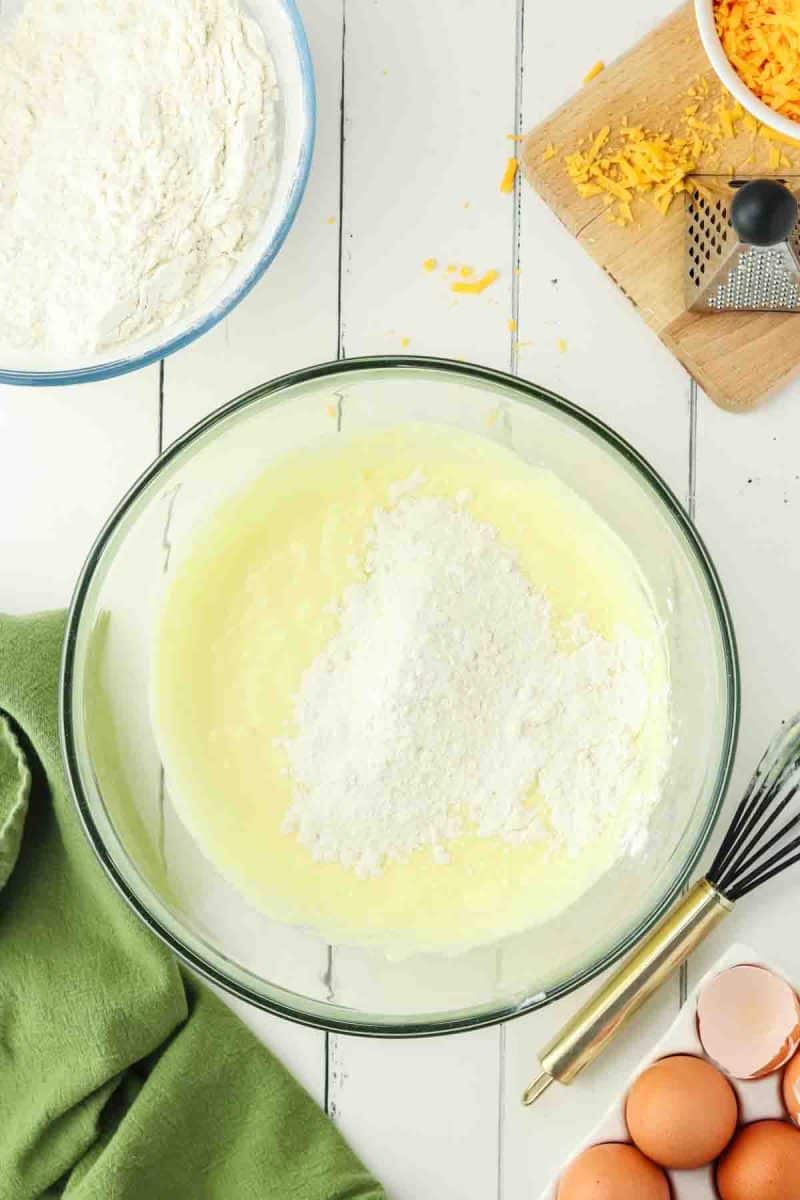 Dry ingredients added to a bowl of wet chedder cheese muffin batter - Hostess At Heart