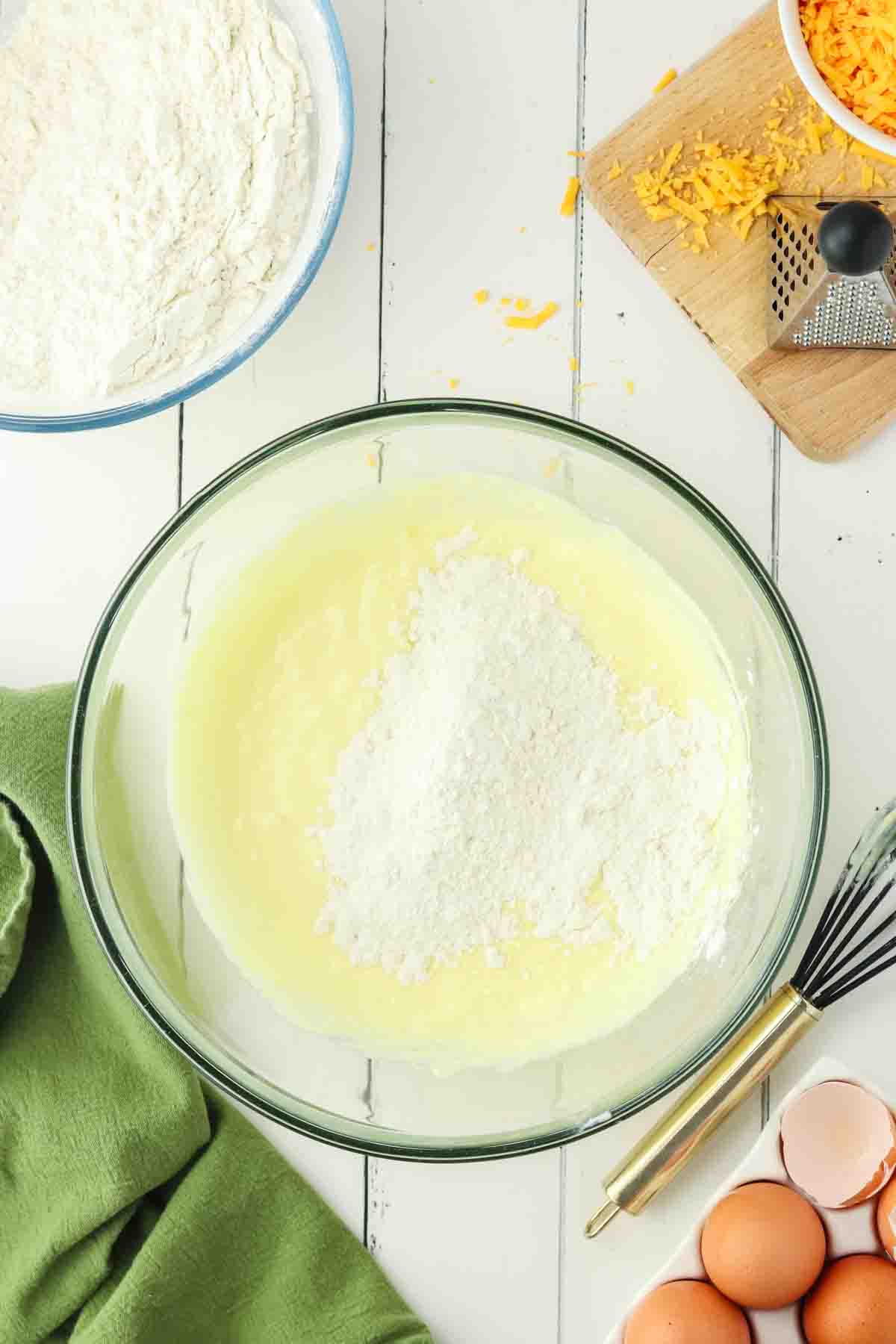 Dry ingredients added to a bowl of wet chedder cheese muffin batter - Hostess At Heart