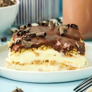 Sideview of no-bake eclair cake slice showing creamy pudding layers between softened graham cracker under a chocolate ganache - Hostess At Heart