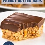 An image for Pinterest of a single peanut butter pretzel bar on white plate with chocolate topping and a bite taken out of it - Hostess At Heart