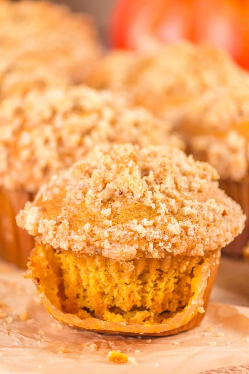 Single sourdough pumpkin muffin with the liner pulled down showing a moist tender interior and a crunchy crumble top - Hostess At Heart