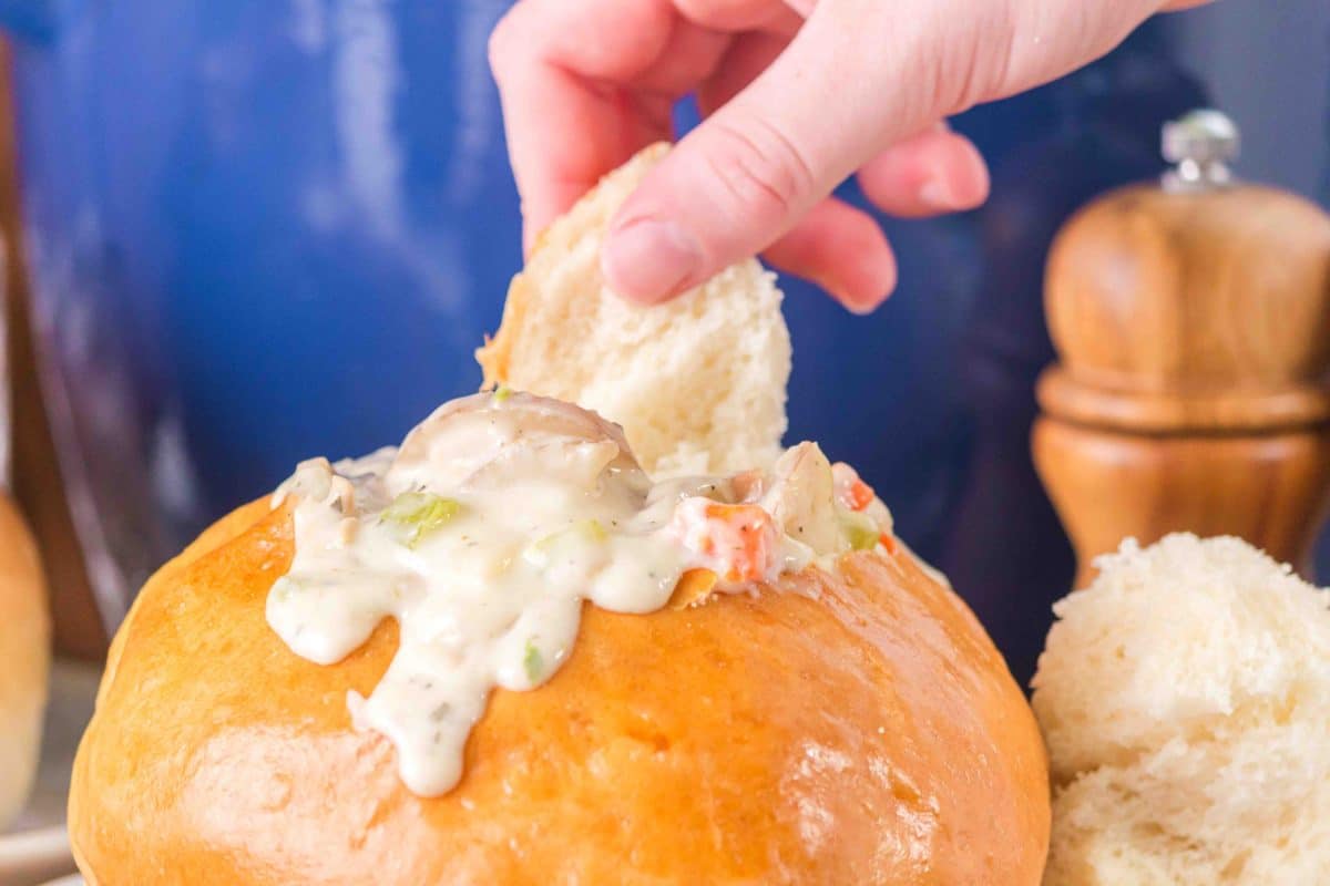 Easy clam chowder bowl recipe served and dripping down the sides of a bread bowl - Hostess At Heart