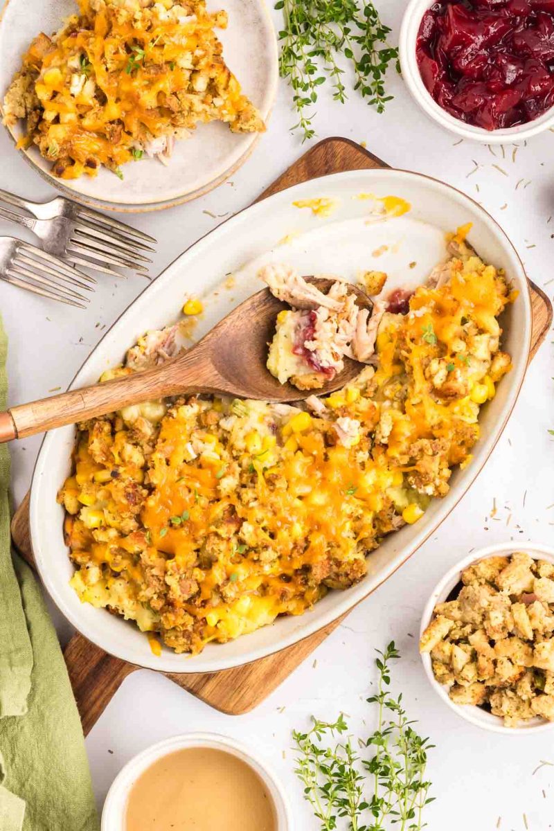 A baking dish filled with a baked Thanksgiving Turkey Casserole with a serving scooped out - Hostess At Heart