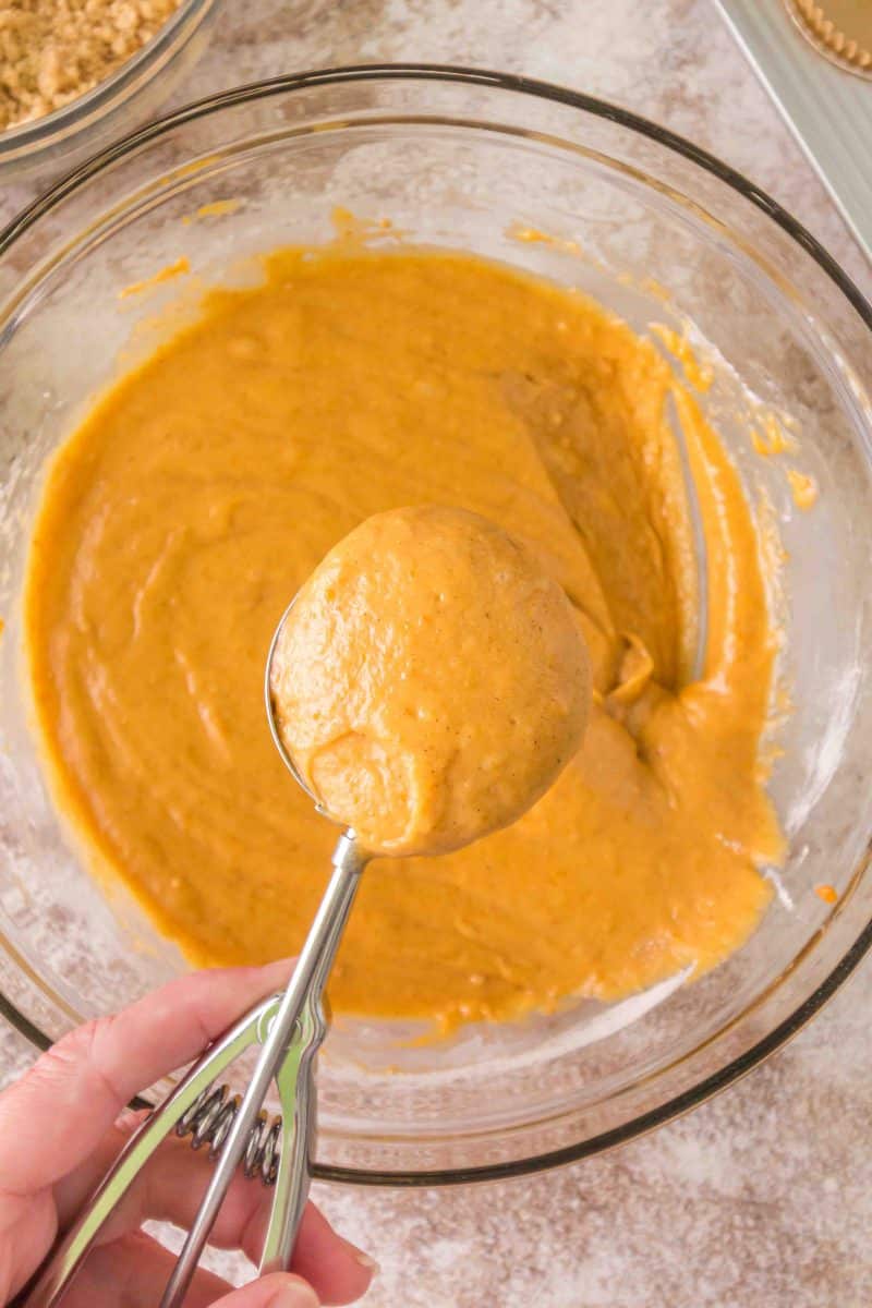 Using a large cookie scoop to fill muffin liners with sourdough pumpkin muffin batter - Hostess At Heart