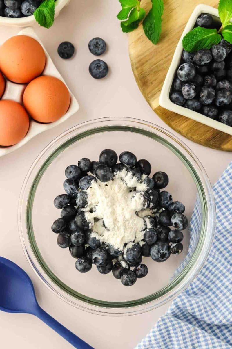 Fresh blueberries coated in flour folded into creamy cheesecake batter in mixing bowl - Hostess At Heart