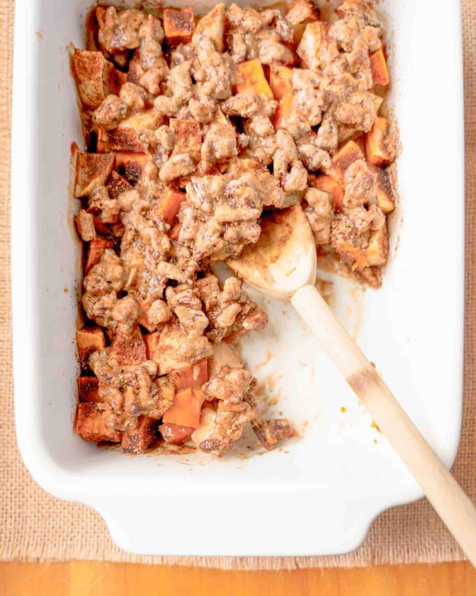 Partly missing healthier sweet potatoes with apple in a casserole dish showing layers of apples and pecans - Hostess At Heart