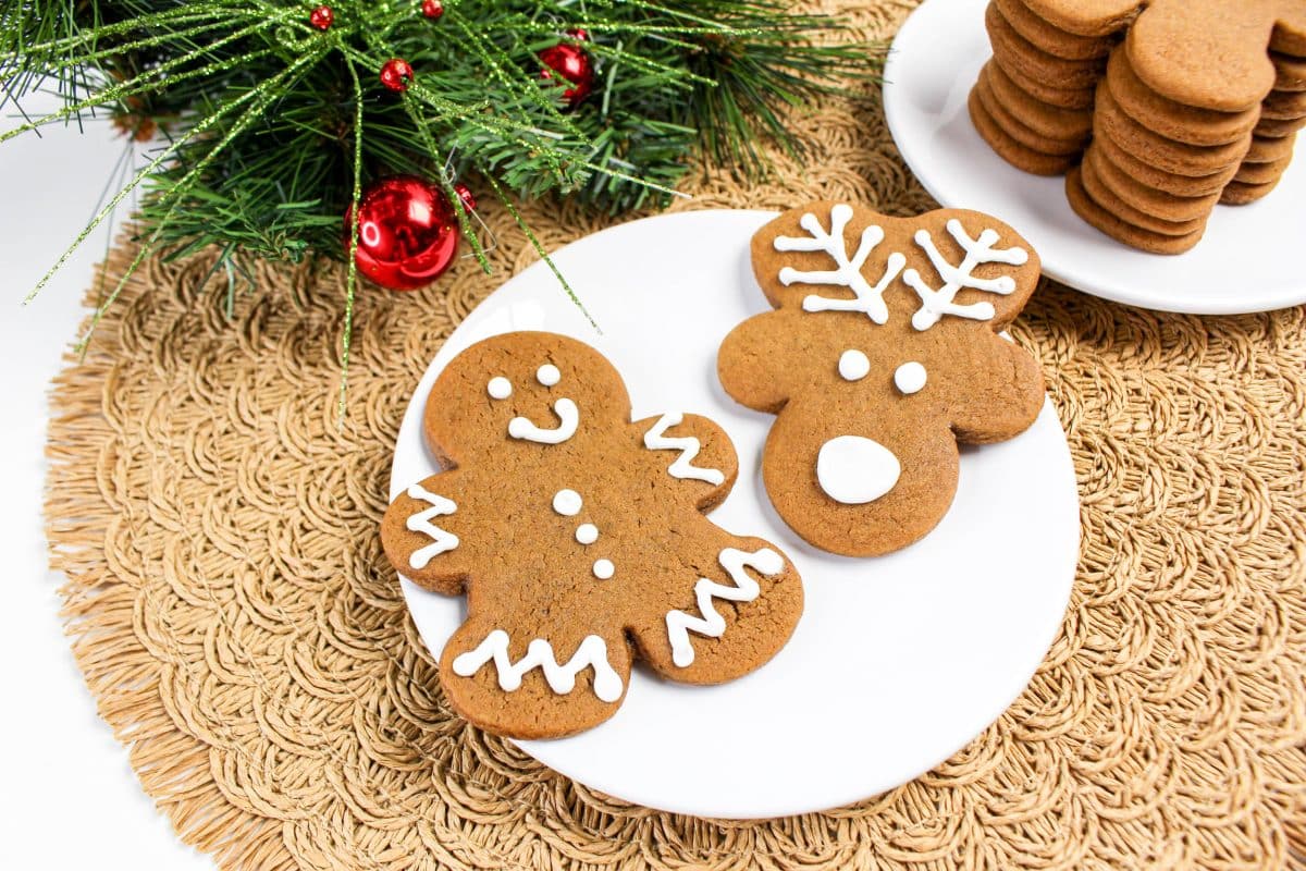 Top down view of a plate holding a decorated gingerbread man cookie and a decorated reindeer cookie. Hostess At Heart