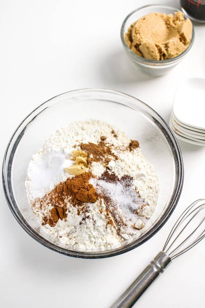 A bowl filled with the dry cookie ingredients: flour, baking soda, cinnamon, nutmeg, cloves, ginger, sugar, and salt. Hostess At Heart