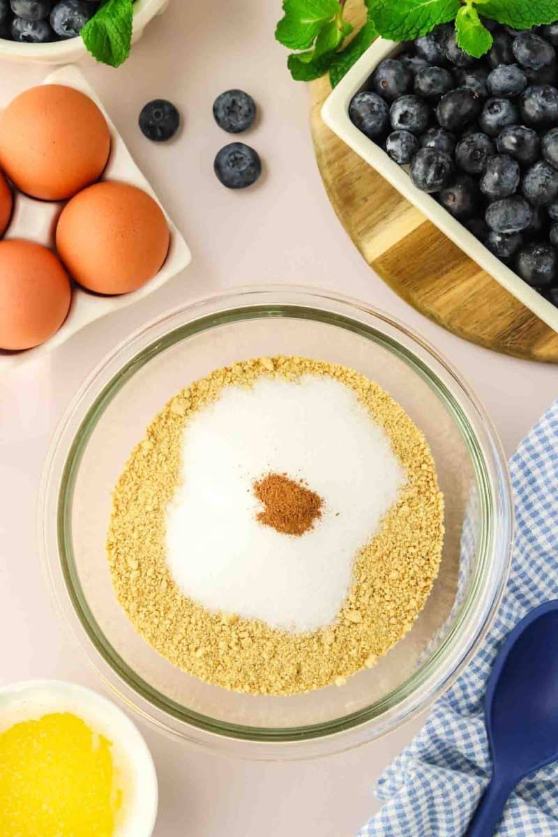 A mixing bowl filled with crushed graham crackers, sugar, and cinnamon - Hostess At Heart