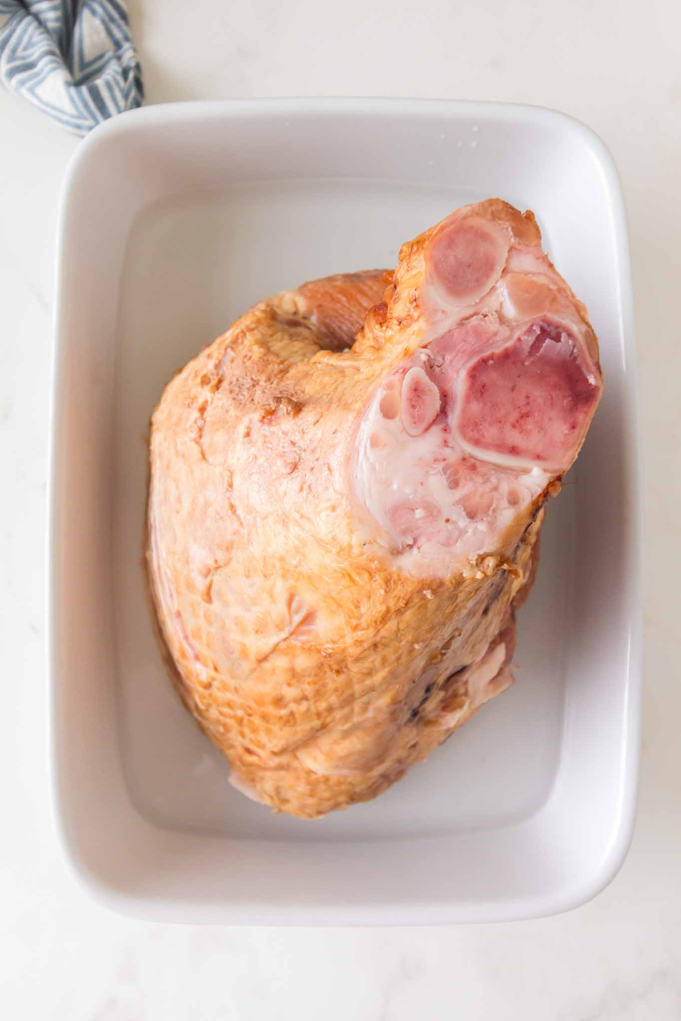 Spiral cut ham placed in baking dish with water before cooking for honey baked ham recipe - Hostess At Heart
