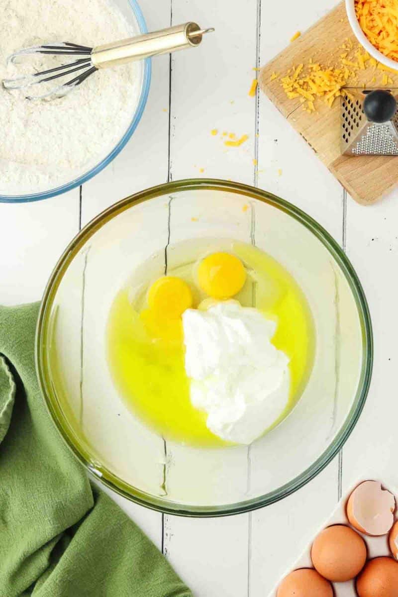 Mixing yogurt, melted butter and eggs for cheddar cheese muffin batter - Hostess At Heart