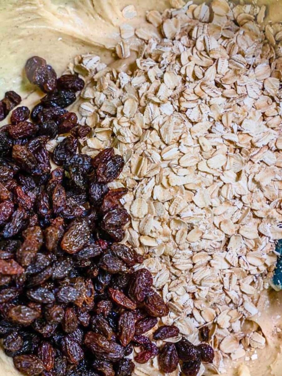 Old fashioned oats and plump raisins added to a creamy oatmeal raisin cookie batter in a large bowl - Hostess At Heart