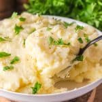 Serving spoon scooping creamy Yukon Gold mashed potatoes from a bowl - Hostess At Heart