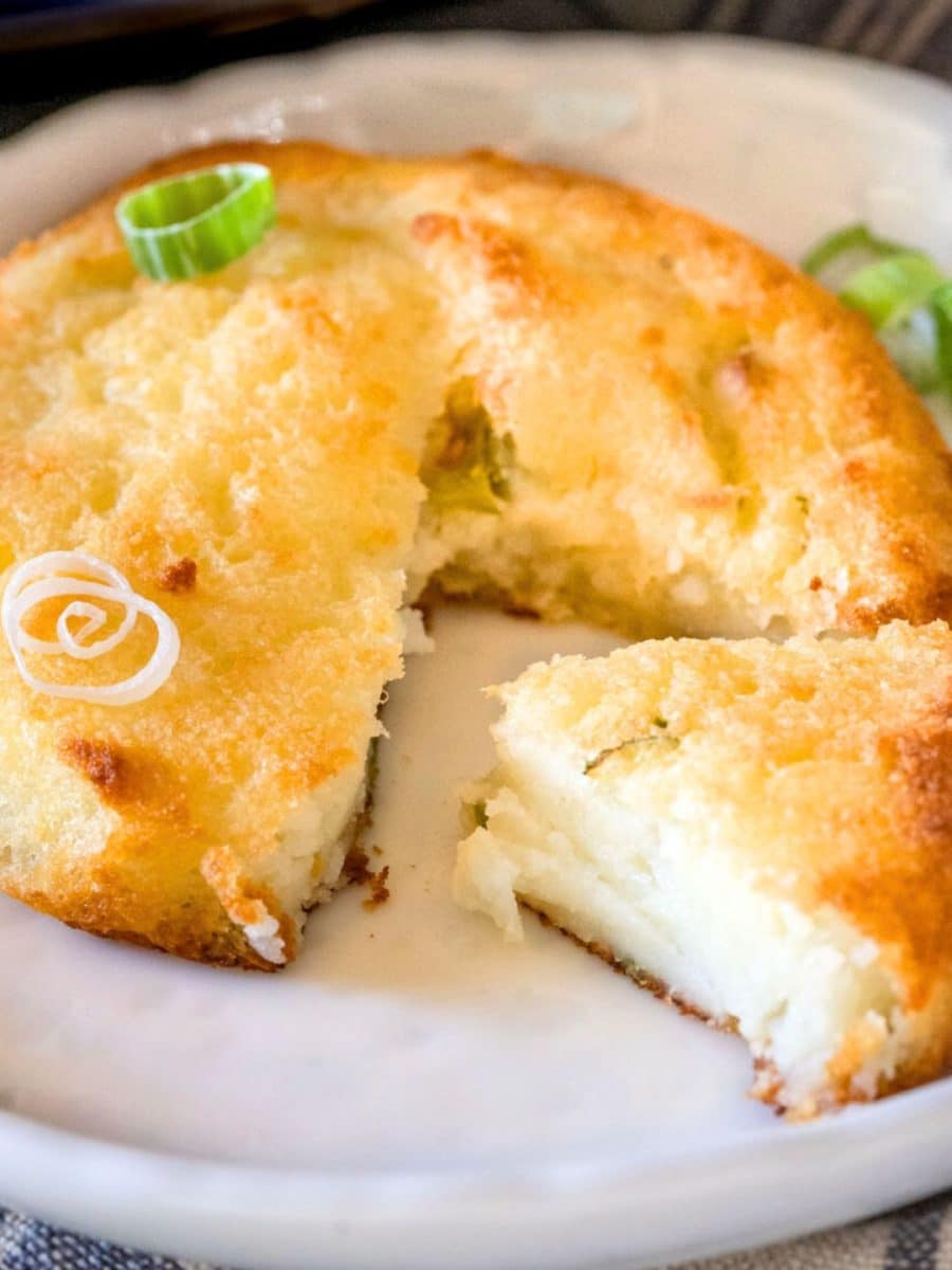 Close up view of a mashed potato patty with a wedge cut from it showing crispy edges and a soft center - Hostess At Heart