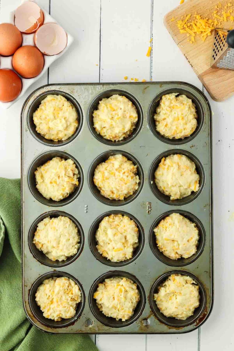 Muffin tin filled with cheddar cheese muffin batter ready to bake - Hostess At Heart