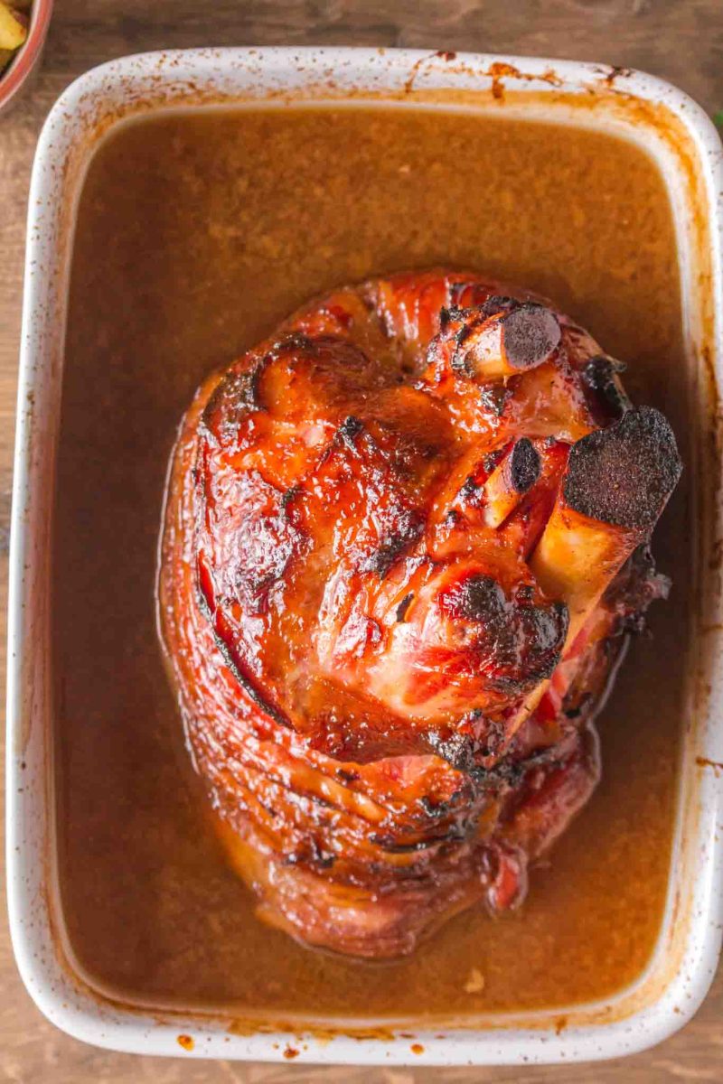 Overhead view of glazed spiral ham in baking dish with golden caramelized coating - Hostess At Heart
