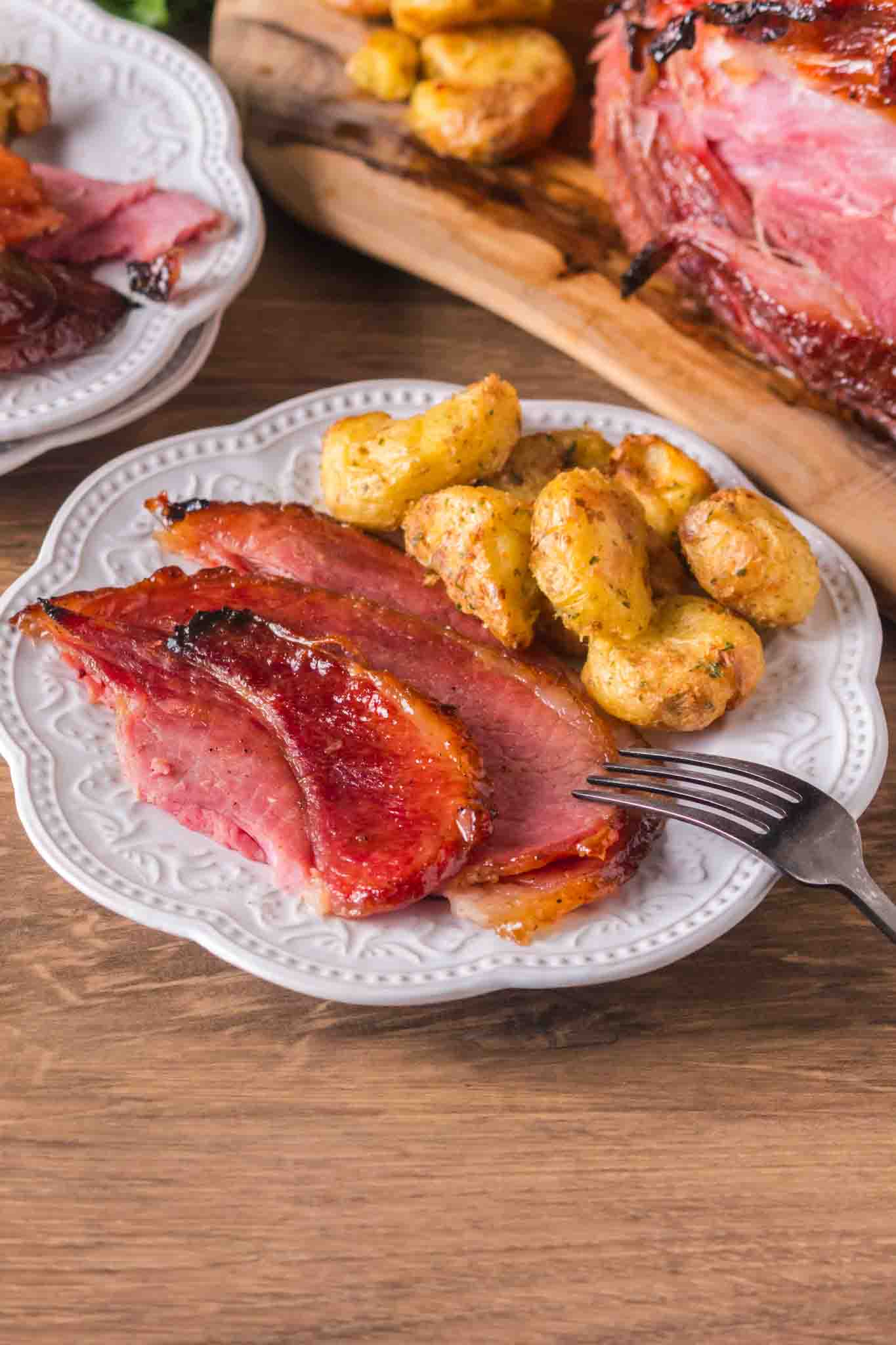 Glazed ham slices served on white plate with creamy smashed potatoes - Hostess At Heart
