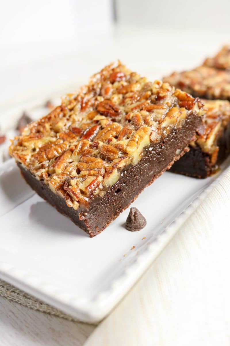 Stack of two pecan pie brownies showing thick gooey chocolate layer under a golden brown pecan topping - Hostess At Heart