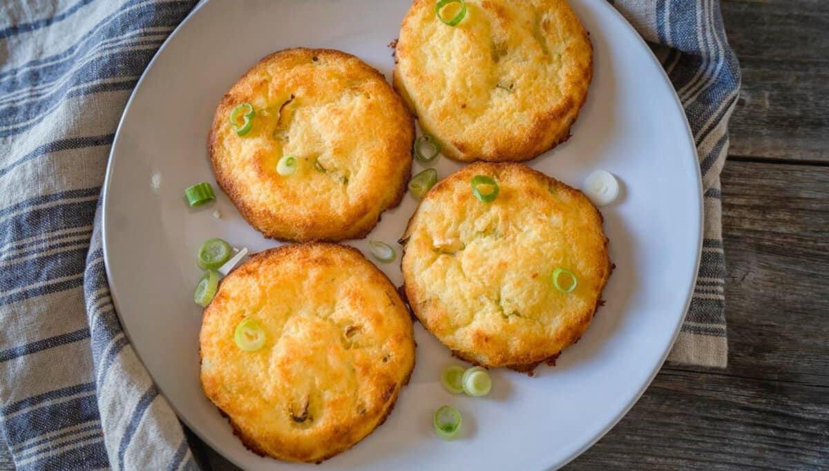 Top down view of 4 potato baked mashed potato cakes garnished with sliced green onions. Hostess At Heart