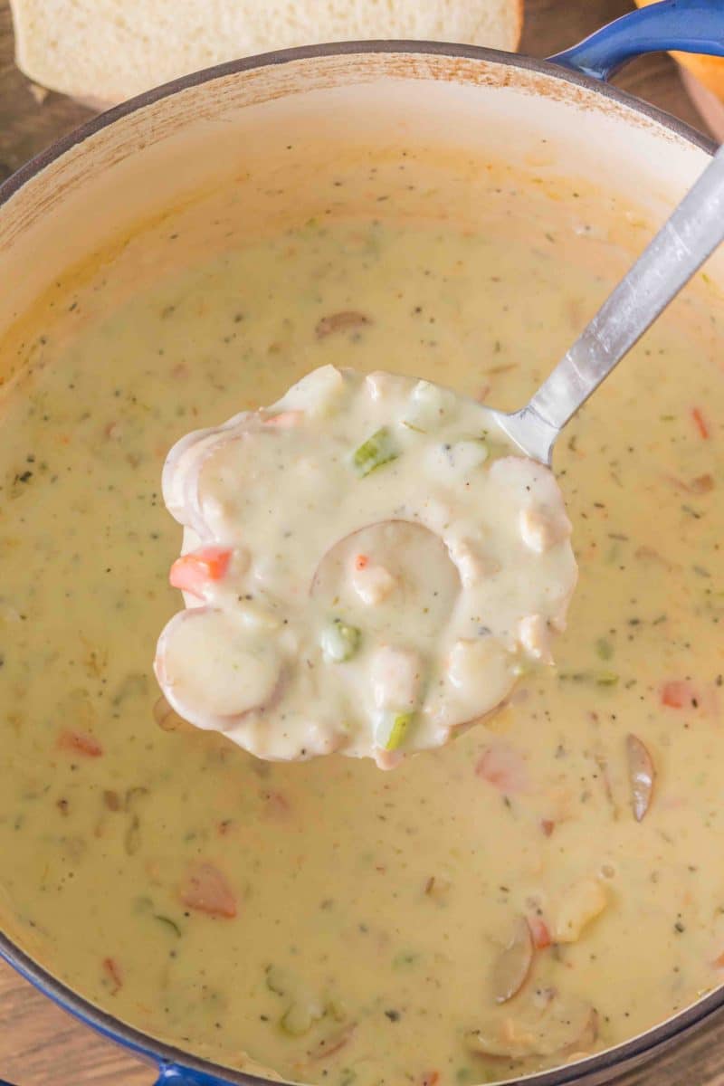 A ladle lifting a serving of thick New England Chowder from a soup pot - Hostess At Heart