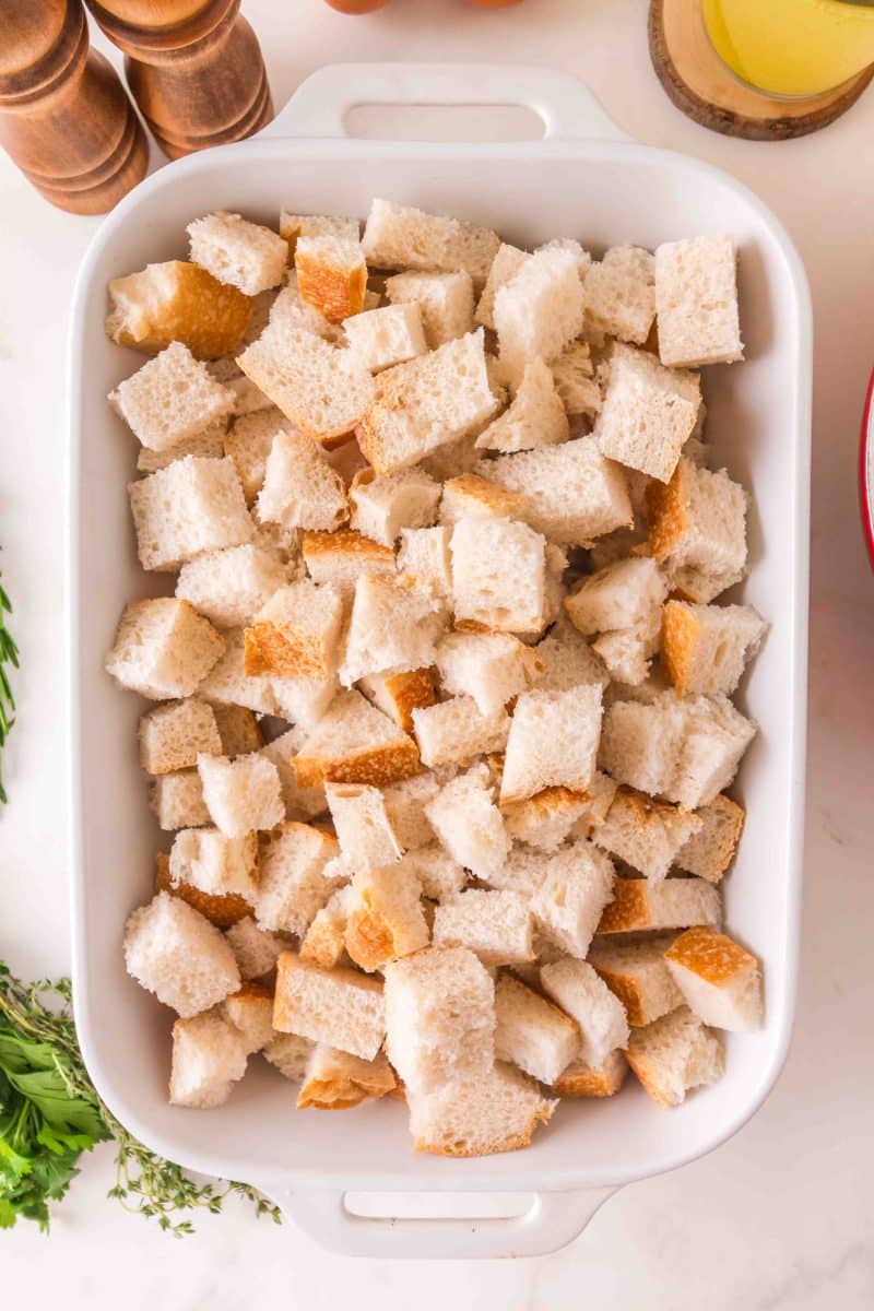Cubed day-old sourdough bread pieces on a baking dish ready for stuffing recipe - Hostess At Heart