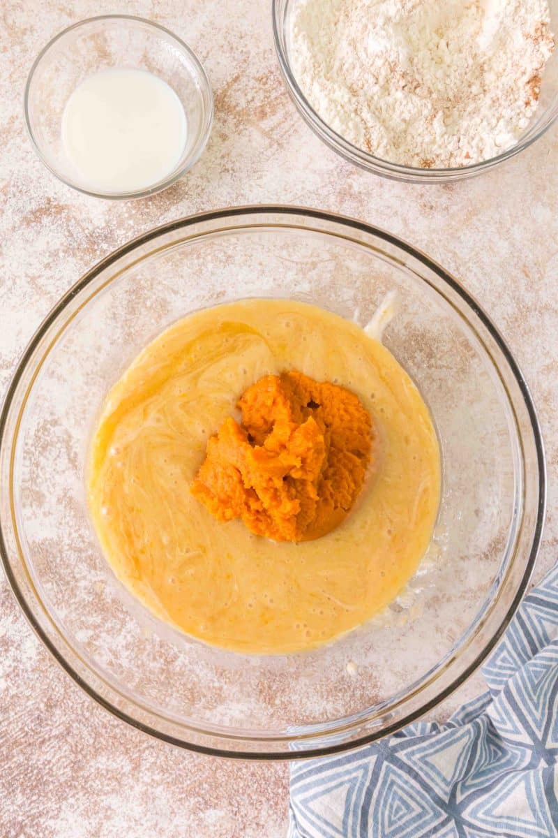 Pumpkin Puree added to a mixing bowl filled with sourdough discard ingredients: oil, sugar, eggs, sourdough discard - Hostess At Heart