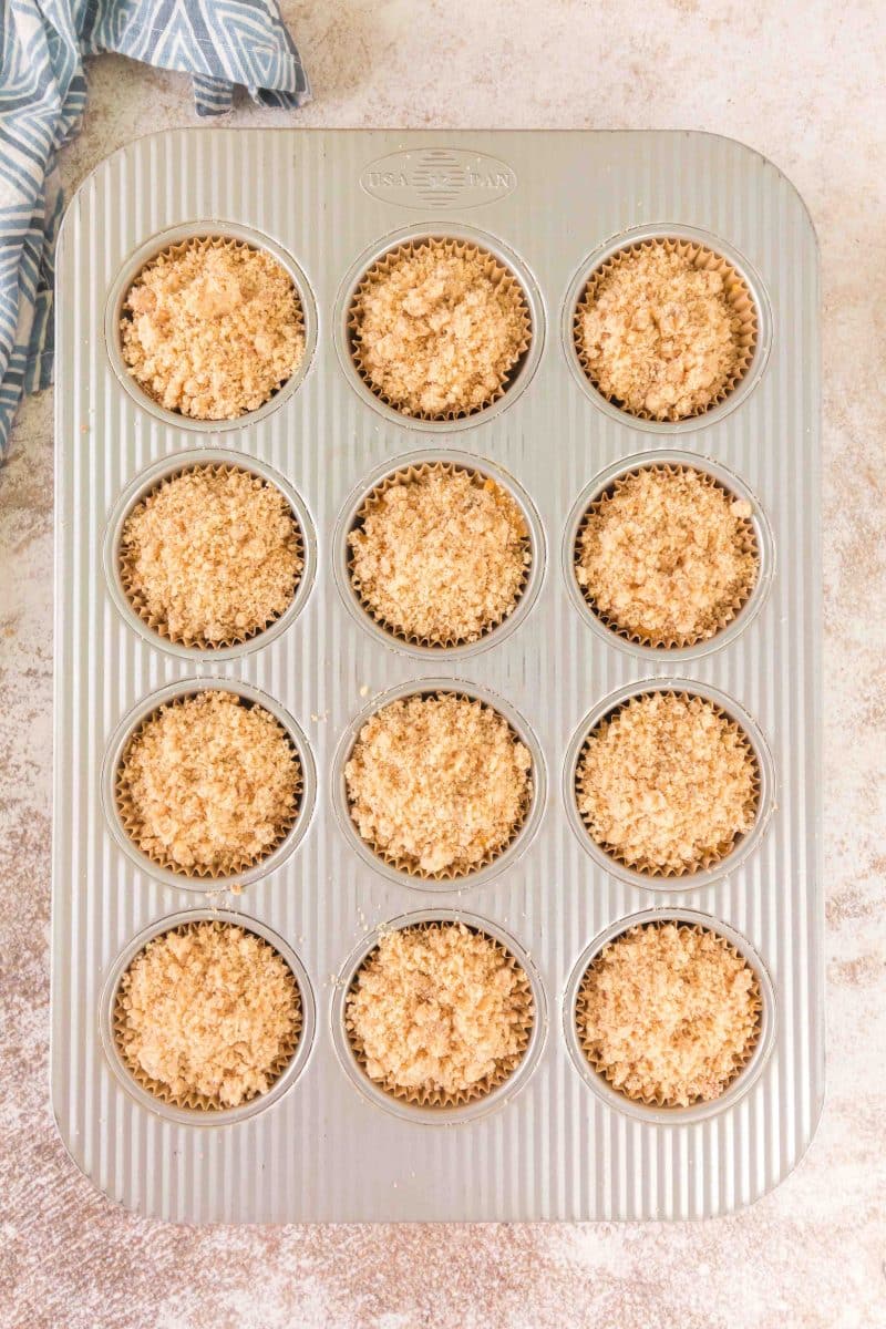 Filled muffin liners with sourdough pumpkin muffin batter and topped with crumble - Hostess At Heart