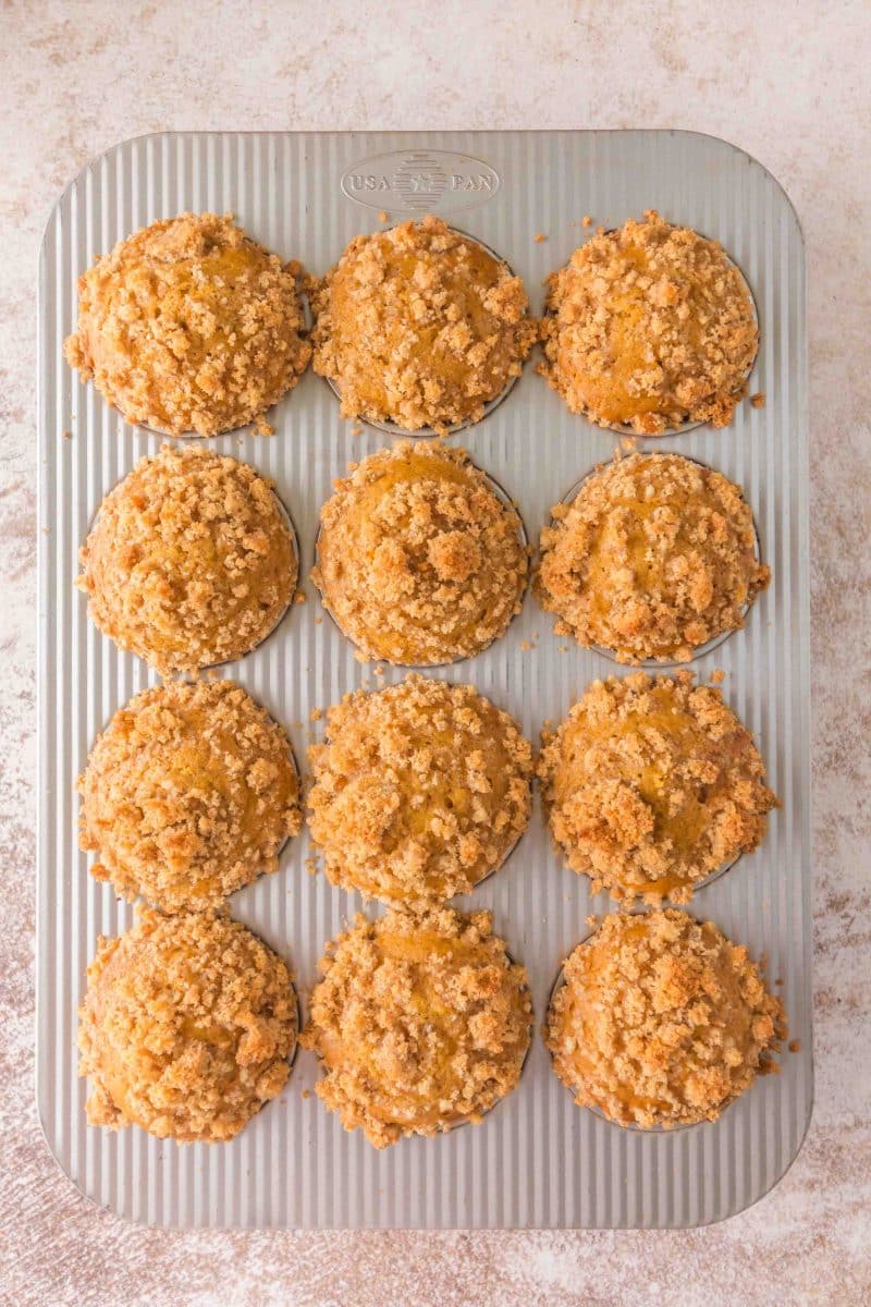 Overhead view of golden brown baked sourdough discard pumpkin muffins with crunchy brown sugar crumble topping in a muffin tin - Hostess At Heart