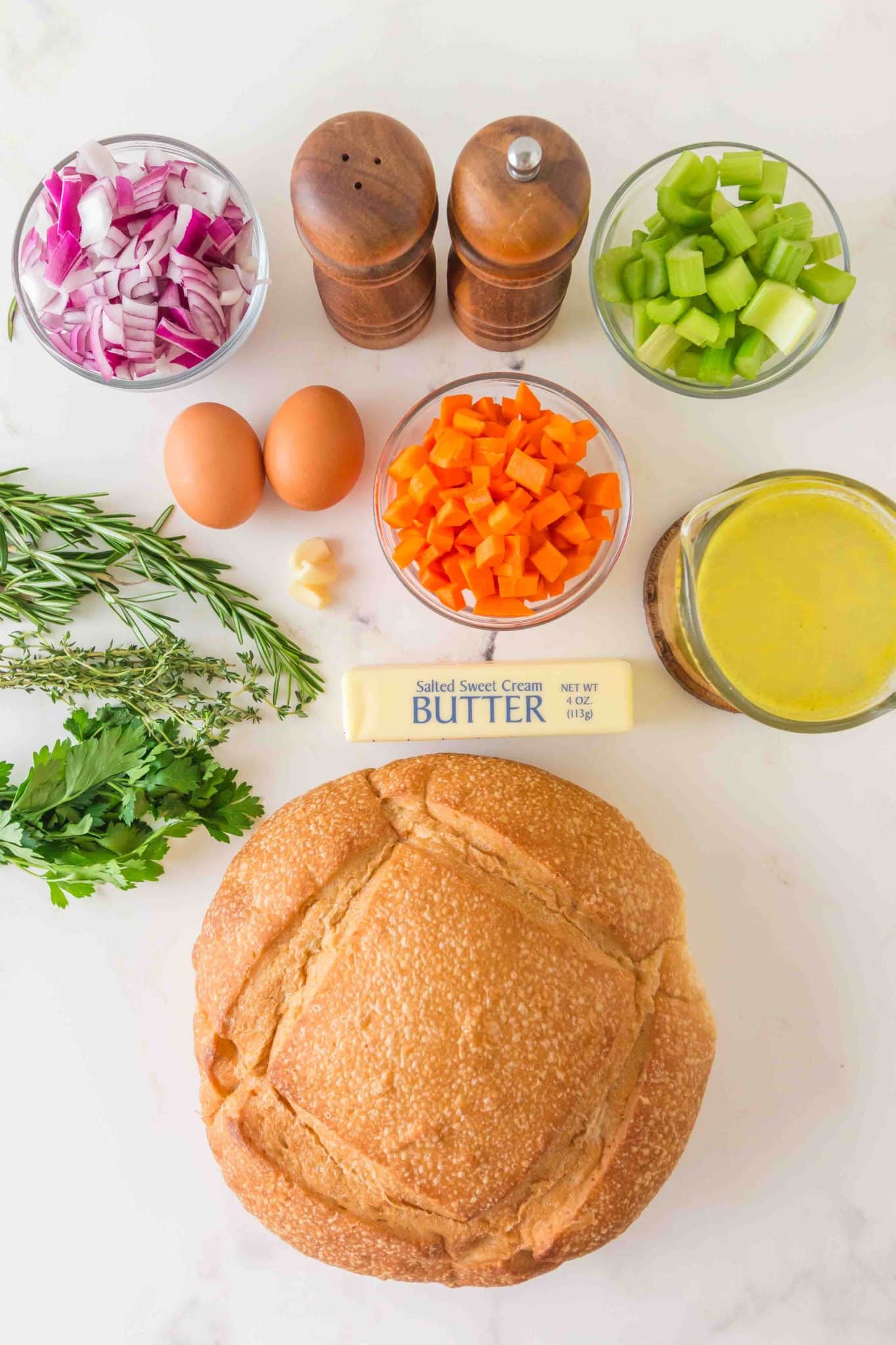 Sourdough Stuffing Recipe Ingredients: A loaf of sourdough, diced onion, carrots, and celery, butter, eggs, salt, pepper, fresh rosemary, parsley, thyme, and chicken broth - Hostess At Heart
