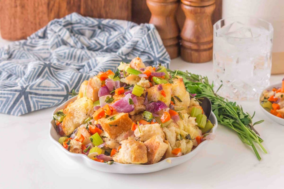 Golden brown sourdough stuffing in a white baking dish with crispy edges and fresh herbs - Hostess At Heart