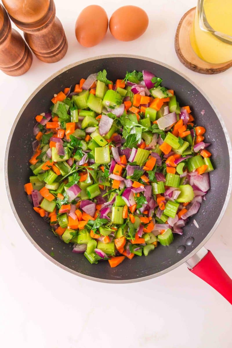 Diced onions, celery, and carrots sautรฉing in butter with fresh herbs for sourdough stuffing - Hostess At Heart