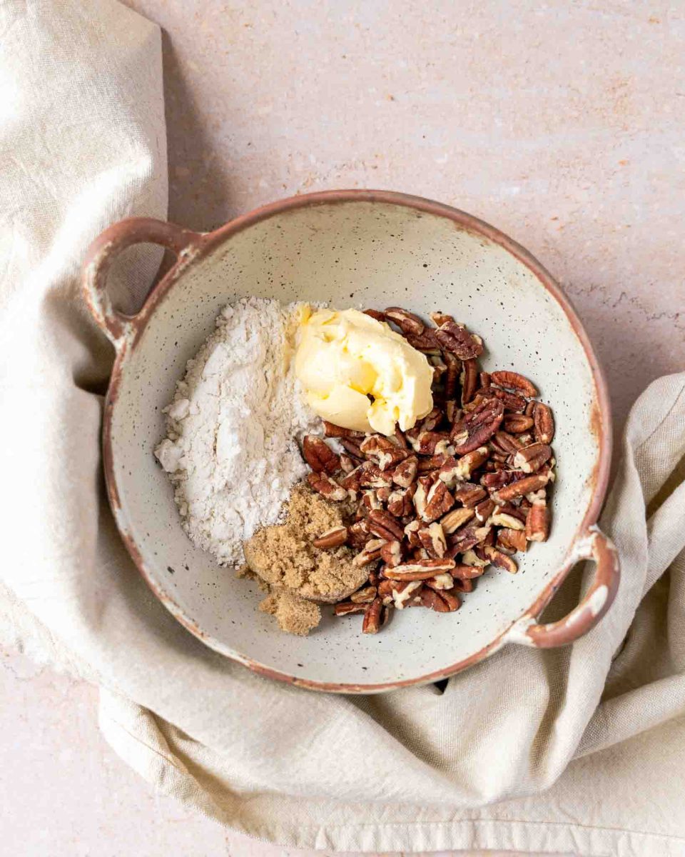 A small bowl filled with pecan topping mixture including butter, brown sugar, pecans, and flour - Hostess At Heart