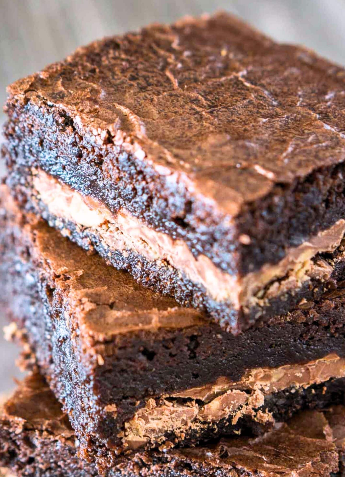 Close up view of a stack of dark chocolate toffee brownies showing a moist brownie with a crunch candy bar layer running through the center - Hostess At Heart