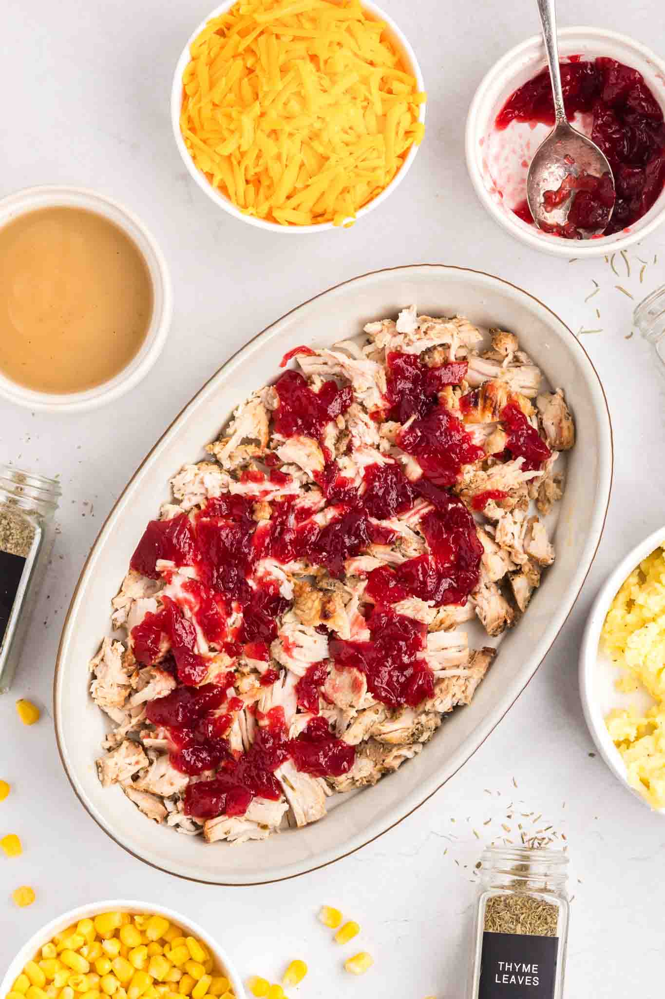 Cranberry sauce dolloped over turkey in casserole dish - Hostess At Heart