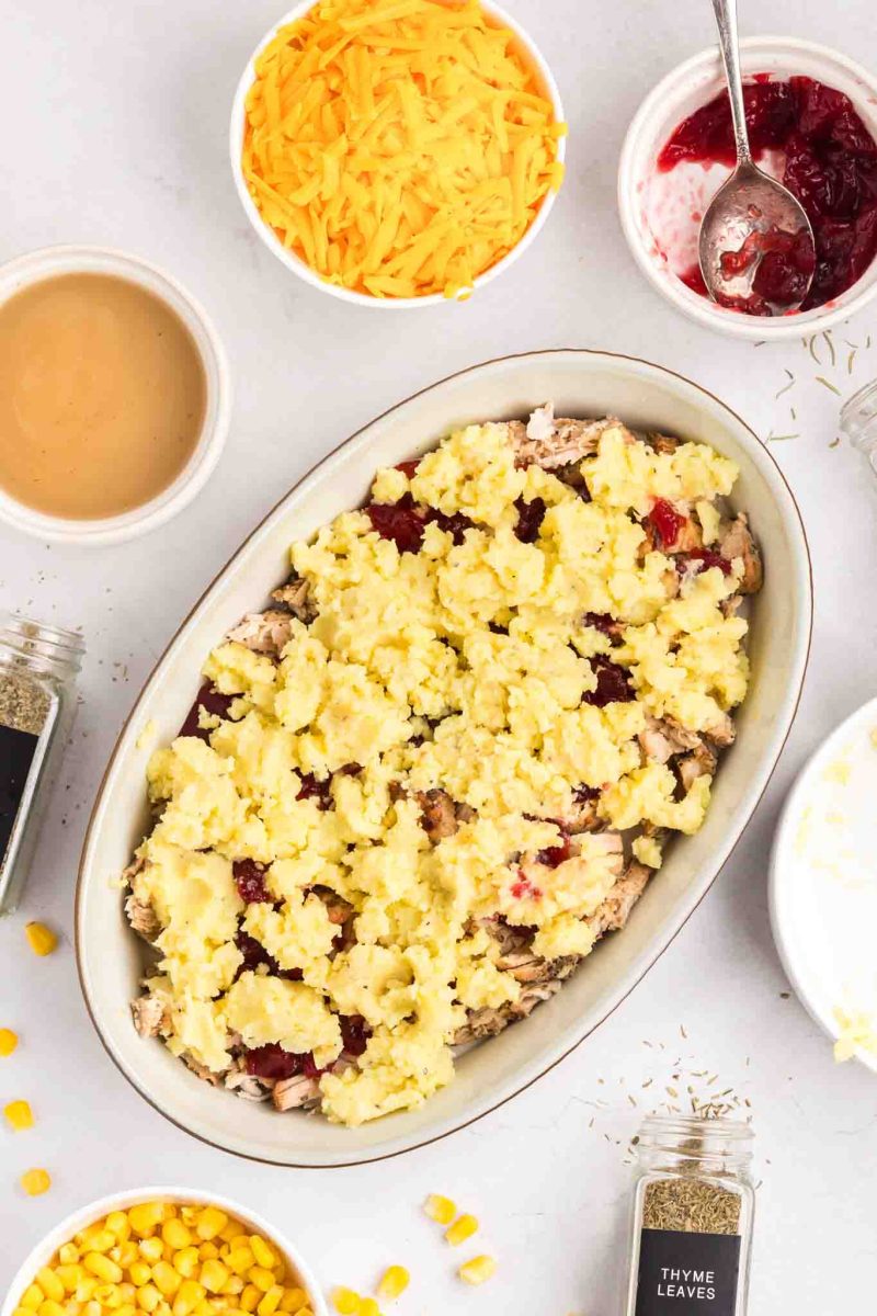 Creamy mashed potatoes layered over turkey and cranberry sauce in baking dish - Hostess At Heart