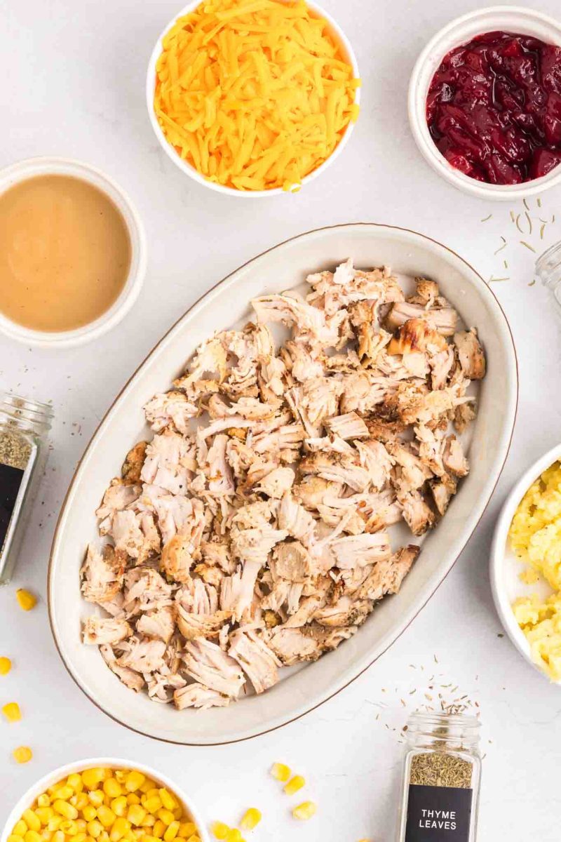 Shredded turkey spread in the bottom of a baking dish for leftover casserole - Hostess At Heart