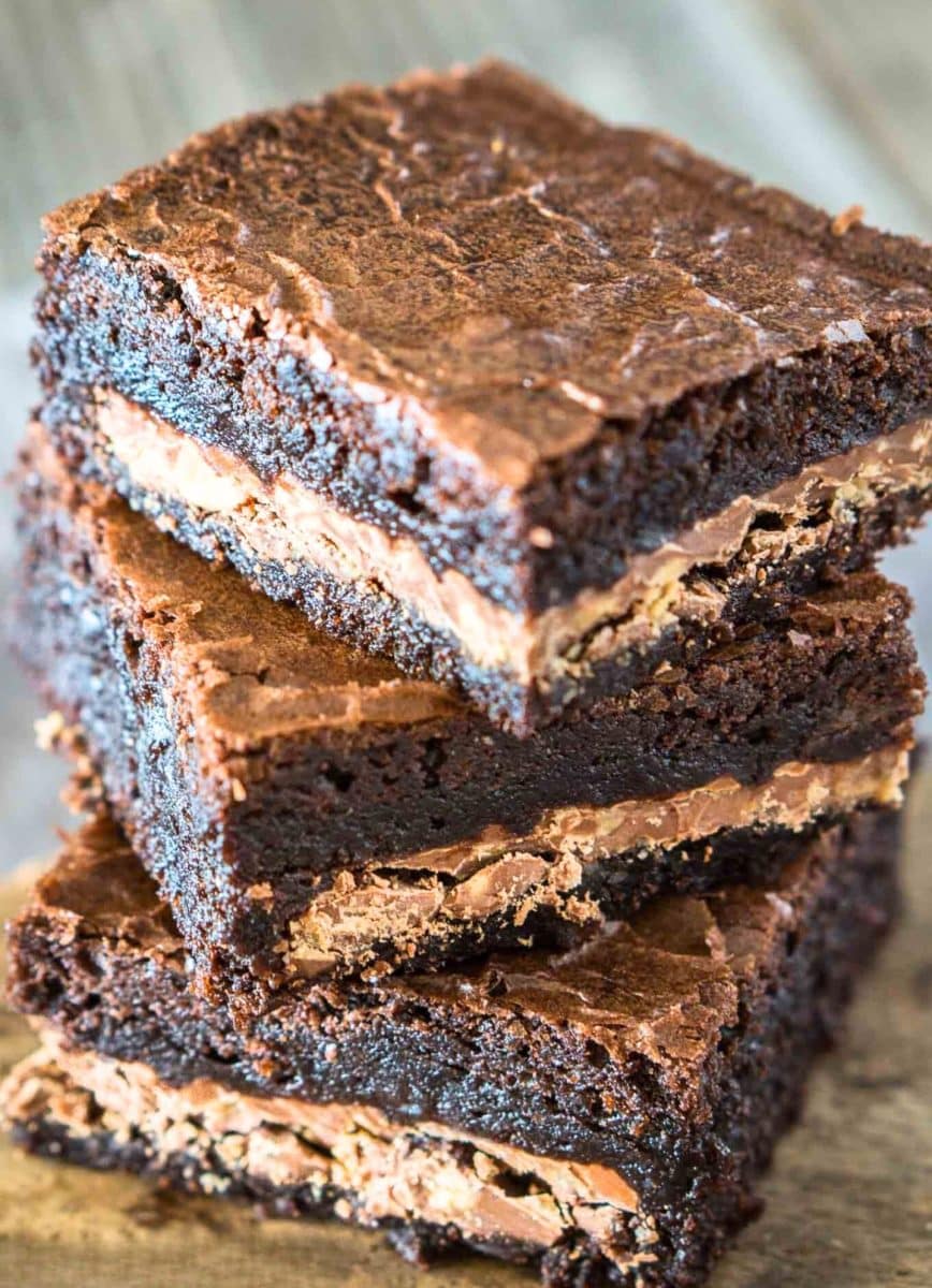 Front view of a stack of 3 glistening dark chocolate brownies with a Symphony candy bar baked into the center. Hostess At Heart