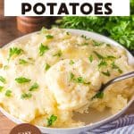 An image for Pinterest of creamy Yukon Gold mashed potatoes in a white serving bowl with melted butter and chopped parsley on top. - Hostess At Heart