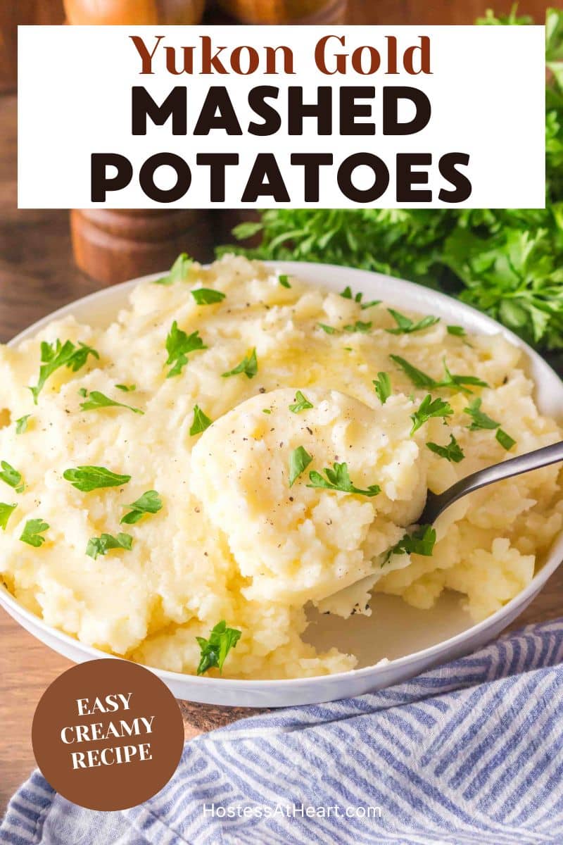 An image for Pinterest of creamy Yukon Gold mashed potatoes in a white serving bowl with melted butter and chopped parsley on top. - Hostess At Heart