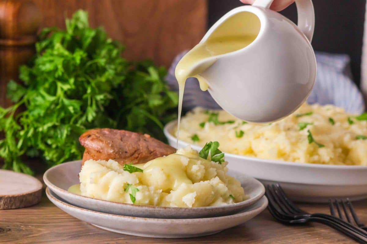 Gravy being poured over a scoop of fluffy Yukon Gold mashed potatoes - Hostess At Heart