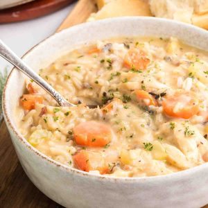 Single serving of chicken and wild rice soup in ceramic bowl garnished with fresh thyme. Hostess At Heart