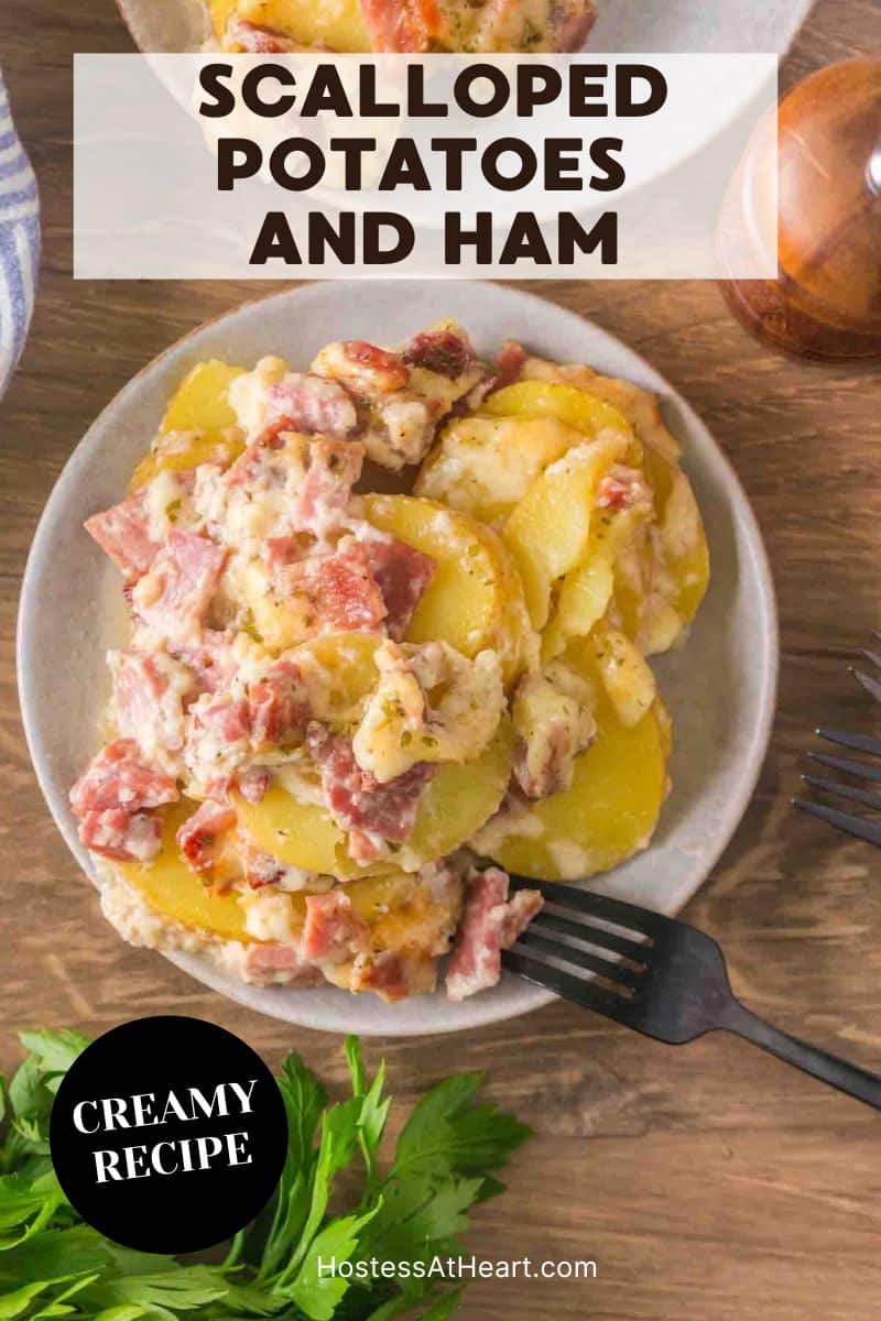 An image for Pinterest of a single serving of scalloped potatoes with ham on plate showing tender potato layers and diced ham in creamy sauce - Hostess At Heart