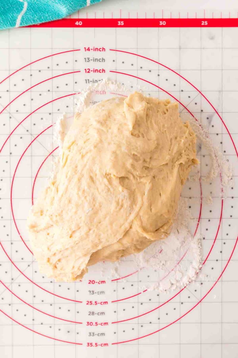 Hawaiian roll bread dough sitting on a floured silicone mat before shaping showing it's soft elastic texture - Hostess At Heart