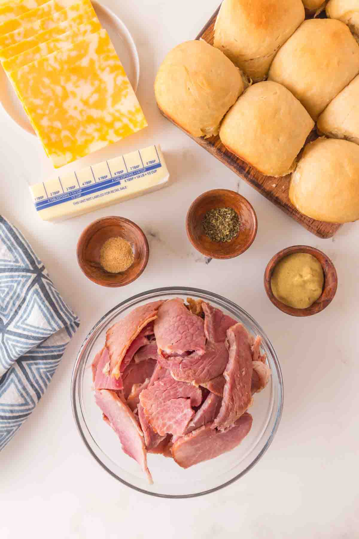 Ingredients to make Hawaiian ham and cheese sliders including Colby cheese, ham, butter, Dijon mustard, Italian seasoning, garlic powder, and Hawaiian Sweet Rolls - Hostess At Heart