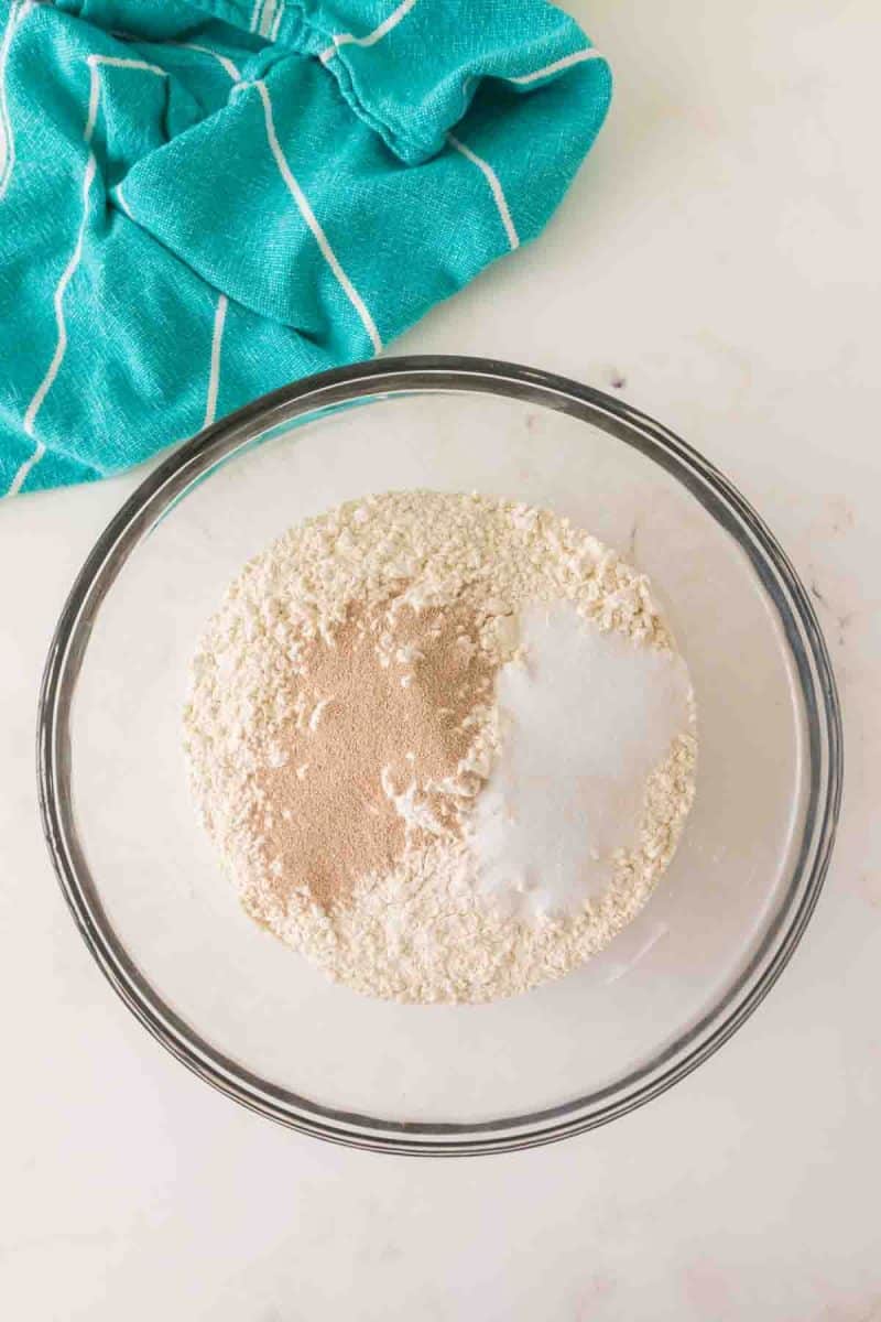 Dry Hawaiian bread roll ingredients added to a mixing bowl including flour, yeast, and salt - Hostess At Heart