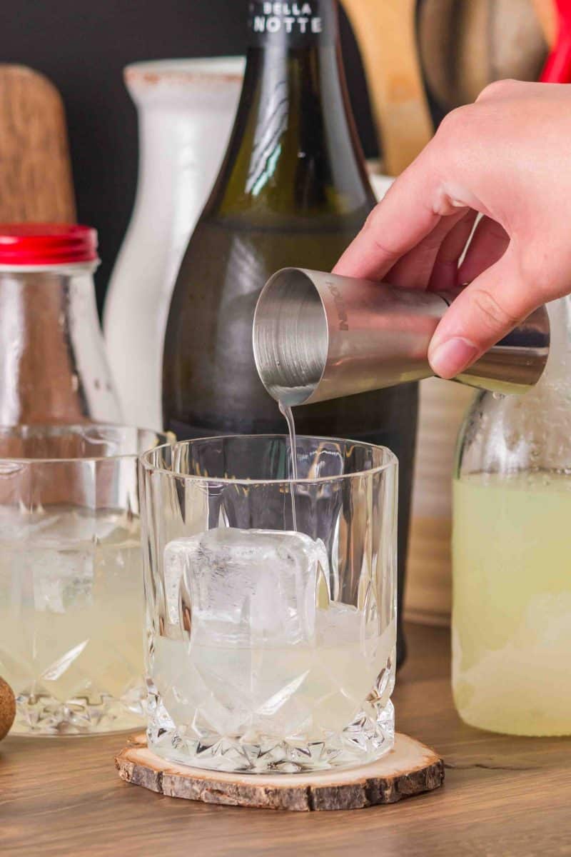 Pouring club soda into a white rocks glass with Limoncello for making a Limoncello Spritz cocktail recipe - Hostess At Heart