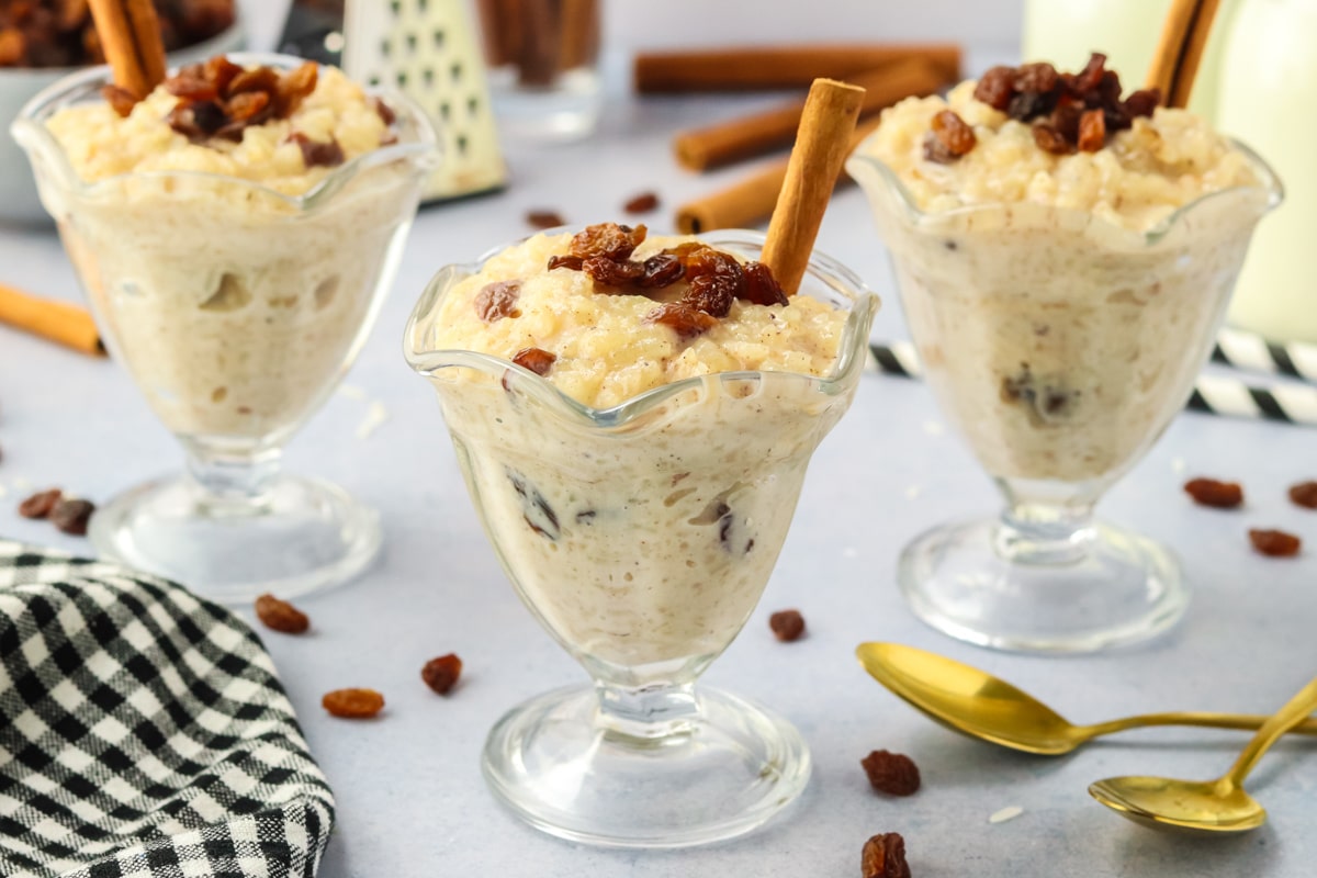 Three dessert cups filled with creamy instant pot rice pudding topped with cinnamon and raisins - Hostess At Heart