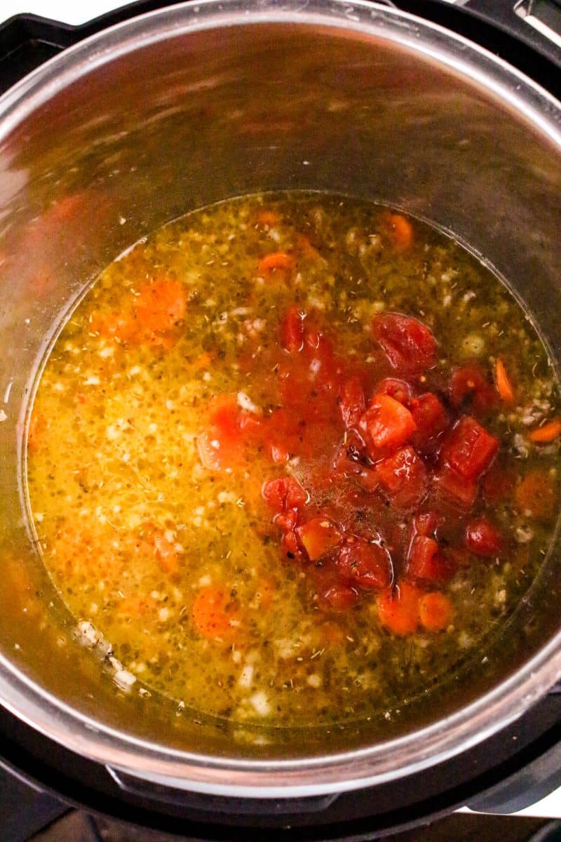 Chicken broth and diced tomatoes added into an Instant Pot with sausage and vegetables - Hostess At Heart