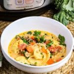 A bowl of Italian Sausage cheese tortellini soup in a creamy broth and wilted kale in white bowl. Hostess At Heart