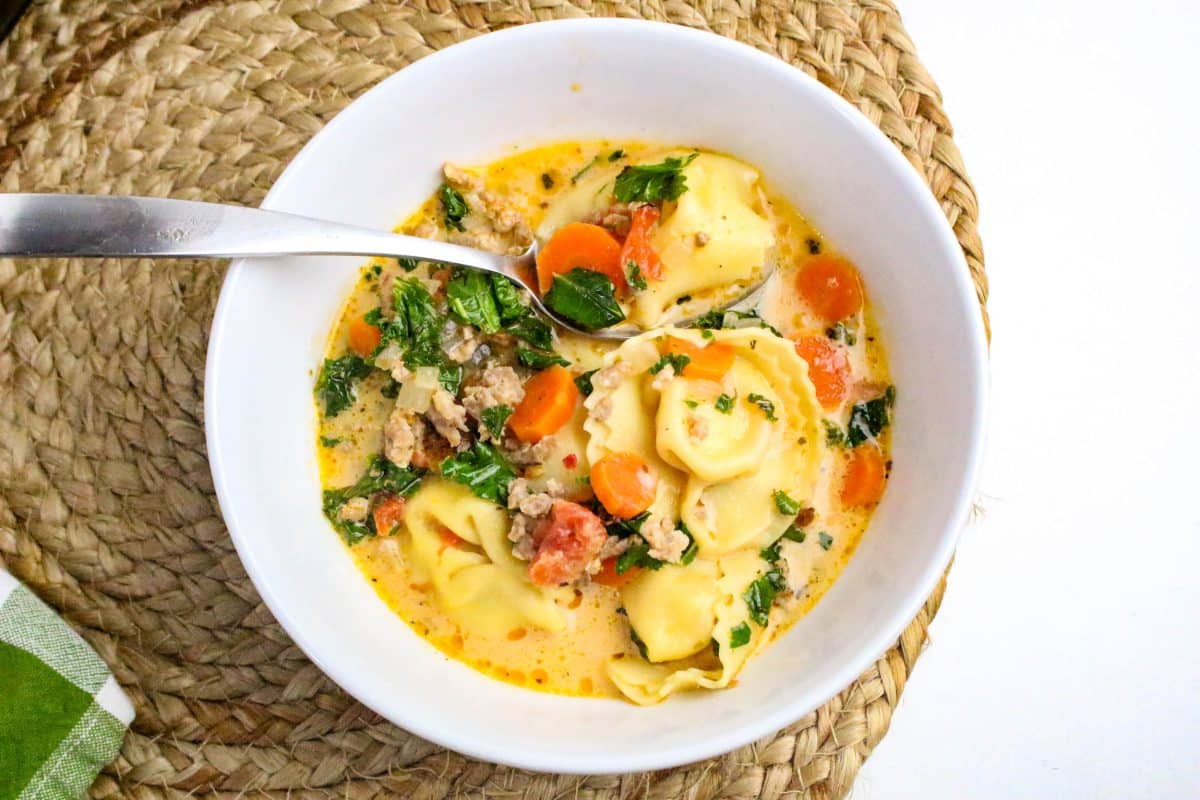 Close-up of cheese tortellini and Italian sausage in creamy tomato broth with wilted kale - Hostess At Heart
